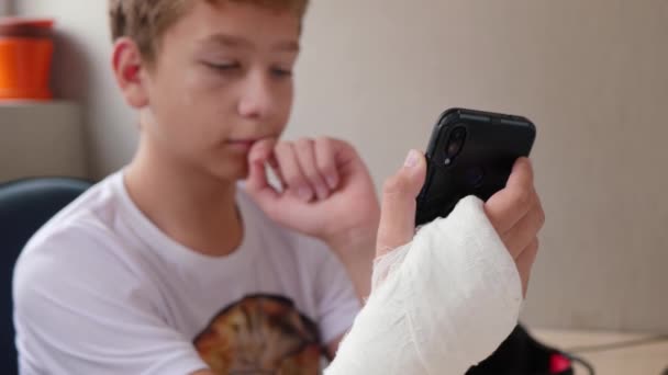 Nastolatek w gipsie używa telefonu — Wideo stockowe