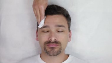 Güzellik uzmanı erkeğin yüzünü yıkar.