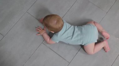 Infant actively examining area, baby crawls on a tiled floor, explore their vibrant world with curiosity, top view