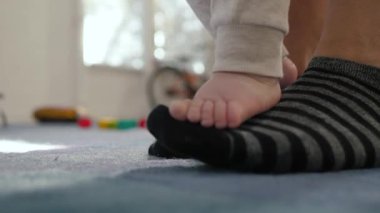 Küçük bir çocuk, ailesinin sevgi dolu desteğiyle bu heyecan verici ilk adımları atar. Evinin sıcak ve hoş atmosferinde güzelce yakalanır. Gerçekten dokunaklı bir andır.