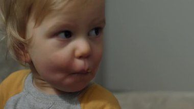 Bir çocuk, masum çocukluk anlarının saflığını somutlaştıran lezzetli bir çöreğin tadını çıkarır. Yakın çekim, seçici odaklanma