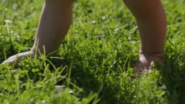Güneşli ayaklar çimlere basar, meraklı bir çocuk bahçeyi çıplak ayakla keşfeder, önemli bir gelişimsel dönüm noktasını gösteren neşeli bir an.