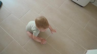 Küçük bir çocuk fayanslı zemindeki odalarda sürünüyor, bebek değişik iç mekanları ve mobilyaları merakla ve ilgiyle keşfediyor.