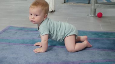 Bebek yumuşak bir halıda sürünerek ilk hareketlerin gelişimini ve bebeklerin parlak dünyalarını keşfetme merakını sembolize eder.