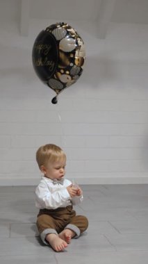 Sevimli küçük bebek renkli bir doğum günü balonuyla oynuyor, saf masumiyet yayıyor.