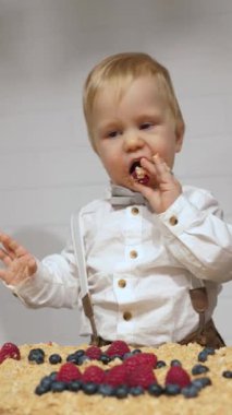 Dağınık bebek ilk doğum gününü büyük bir pastayla kutluyor, saf çocukluk sevinci ve masumiyeti somutlaştırıyor.