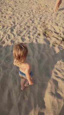 Güneşli bir günde kumlu bir plajda yürüyen küçük bir çocuk, yukarıdan bakıldığında kaygısız atmosfer, çocukluk ve yaz neşesini gösteriyor.