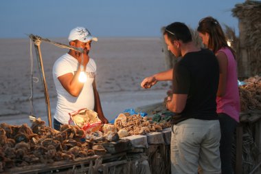 Tourists buying desert rose souvenir at Chott El Jerid clipart