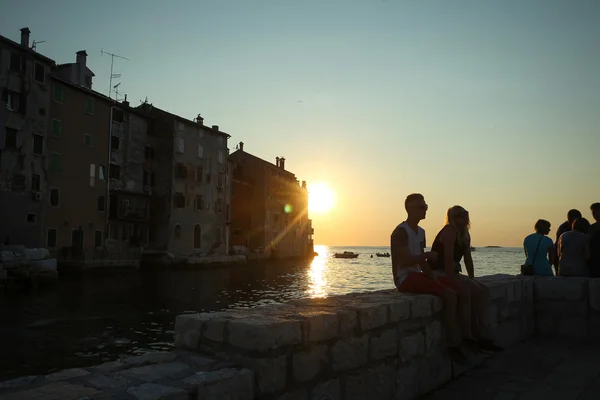 Mensen zitten op kust bij zonsondergang — Stockfoto