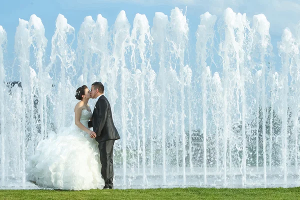 Bruid en bruidegom kussen voor Waterfontein — Stockfoto