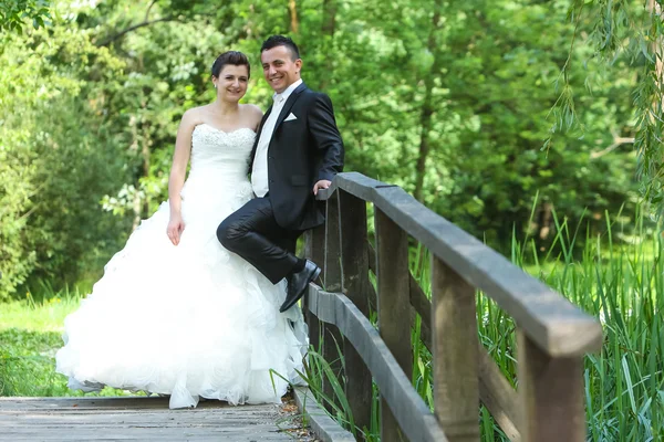 Newlyweds on wooden bridge — Stock Photo, Image