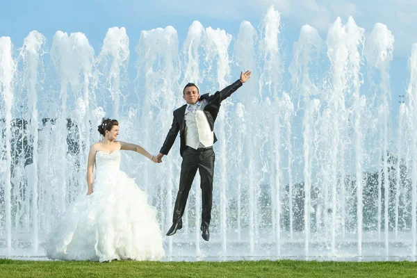 Mariés devant la fontaine de pulvérisation d'eau — Photo