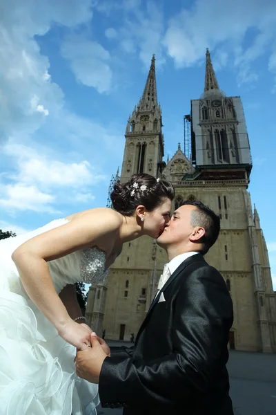 新婚夫妇在大教堂前接吻 — 图库照片