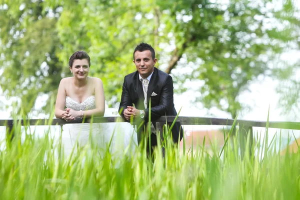 Recién casados posando en puente de madera — Foto de Stock