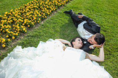 Gelin ve damat çiçekli çim üzerinde yalan