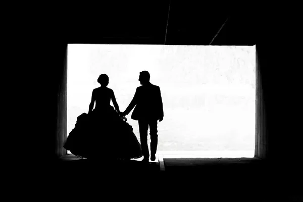 Bride and groom walking in passage bw — Stock Photo, Image