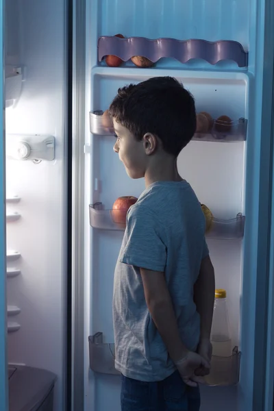 Ребенок смотрит в холодильник посреди ночи — стоковое фото