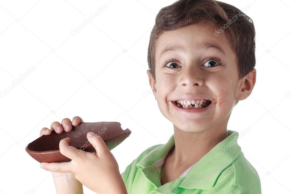 Little boy eating chocolate easter egg on white background