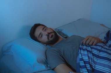 uyku bozukluğu, uykusuzluk. uyanık yatakta yatan genç sakallı adam