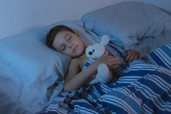 Potret seorang anak kecil tidur dengan boneka beruang di kamar tidur — Stok Foto