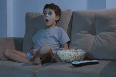 Kanepede televizyon izlerken ve patlamış mısır geceleri yemek küçük çocuk ben