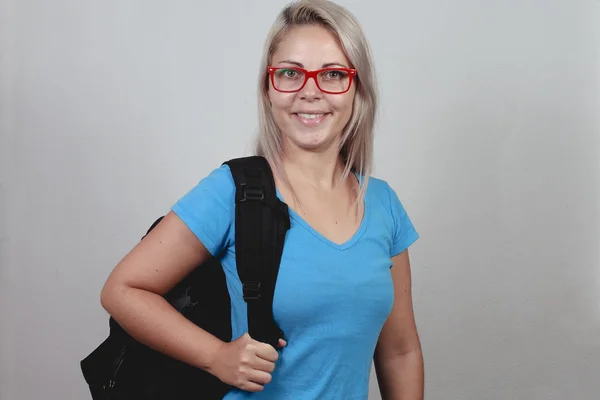 Mladá blondýnka školačka s červenými brýlemi a školní batoh — Stock fotografie