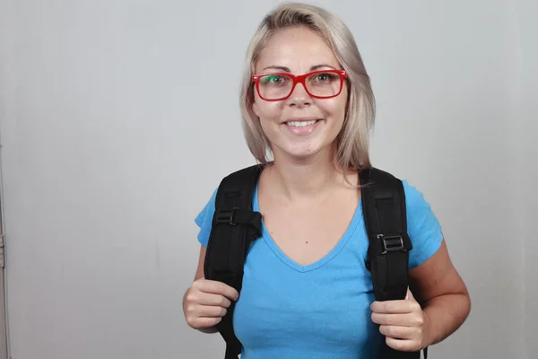 Молодая блондинка в красных очках и школьной сумке — стоковое фото