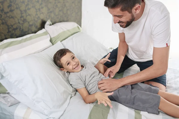 Ο πατέρας που γαργαλάει το γιο του στο κρεβάτι — Φωτογραφία Αρχείου