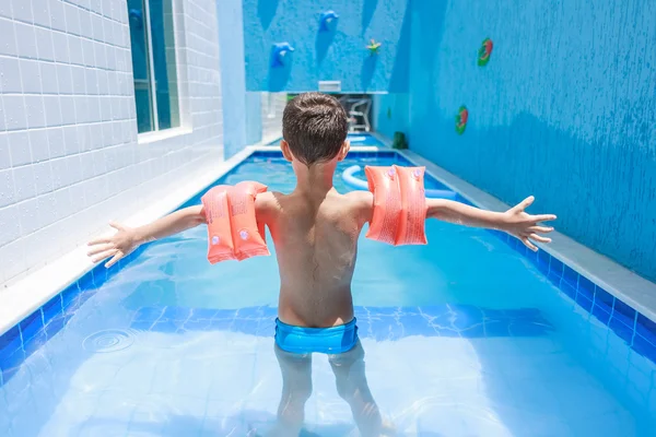 Süßer kleiner Junge im Badeanzug mit Arm schwimmt im Pool — Stockfoto