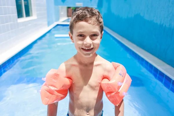 Süßer kleiner Junge im Badeanzug mit Arm schwimmt im Pool — Stockfoto