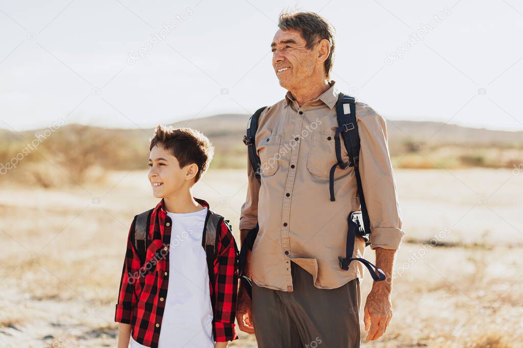 Latin grandfather and grandson with backpacks hiking in the mountains.