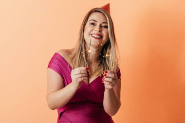 Renkli arka planda parti şapkası takan genç bir kadının portresi