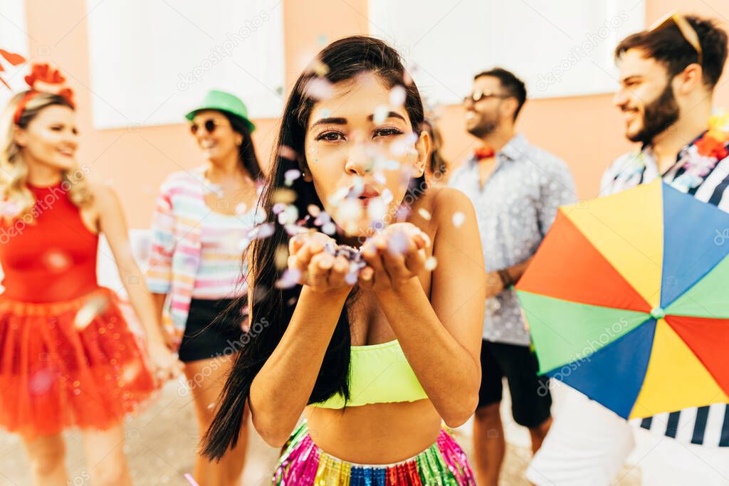 Brazilian Carnival. Young woman enjoying the carnival party blowing confetti