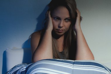 uyku bozukluğu, uykusuzluk. Genç sarışın kadın yatakta oturuyordu bir