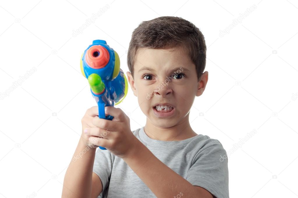 Little boy with funny expression playing with plastic water gun 