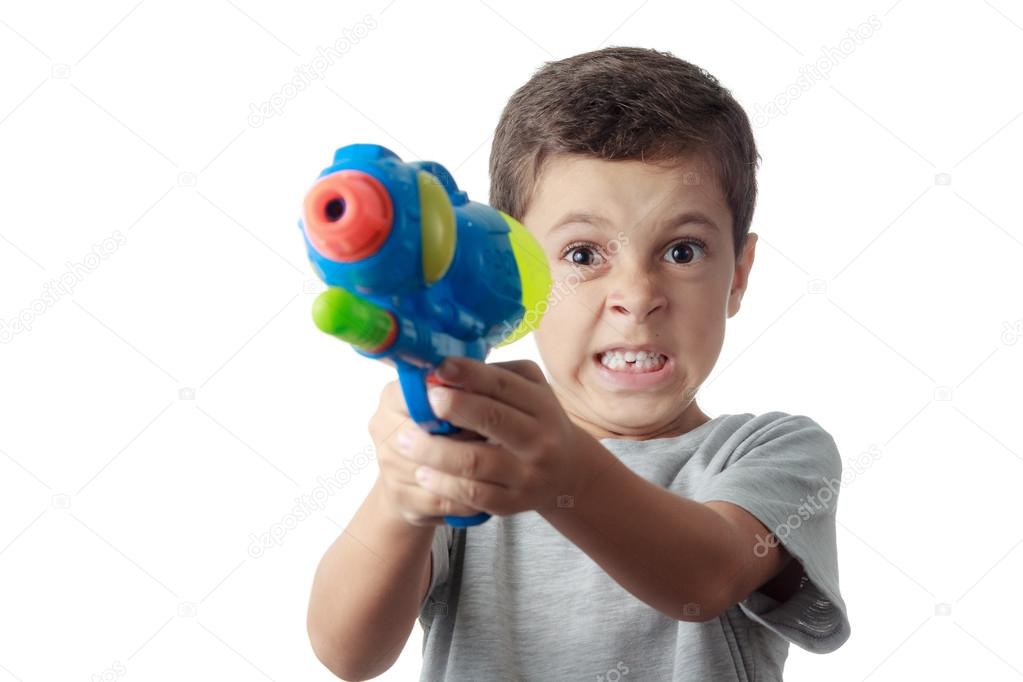 Little boy with funny expression playing with plastic water gun 