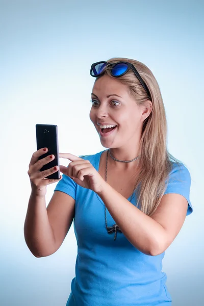 Mujer sorprendida mirando el smartphone. Usando camisa con s azul —  Fotos de Stock