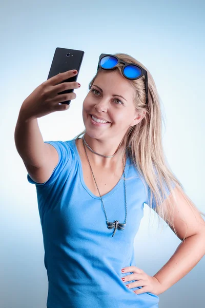 Mujer tomando autorretrato con smartphone. El uso de una camisa azul —  Fotos de Stock