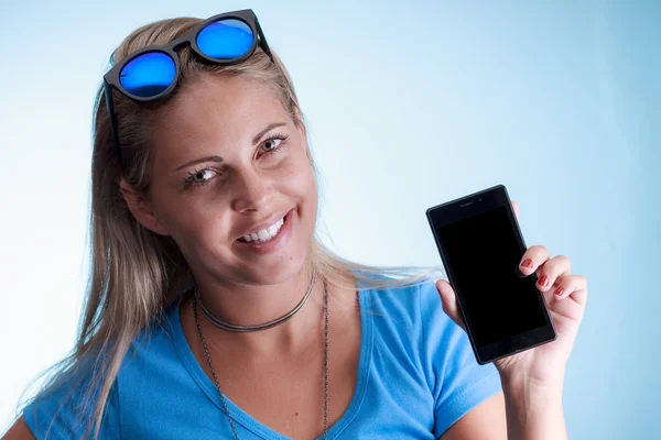 Mujer hermosa joven mostrando pantalla de teléfono inteligente en blanco sobre azul —  Fotos de Stock