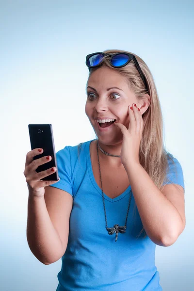 Mujer sorprendida mirando el smartphone. Usando camisa con s azul —  Fotos de Stock