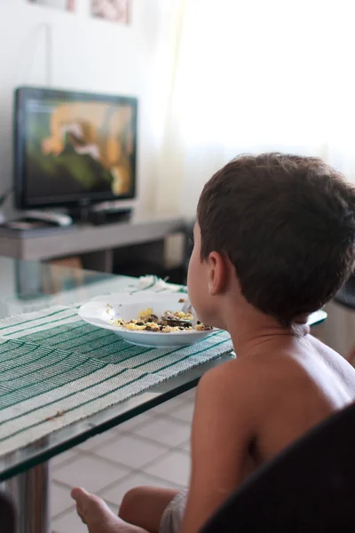 Bambino distratto guardando la tv mangiare pranzo — Foto Stock
