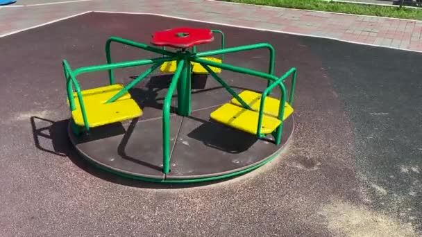 遊び場で回転する緑と黄色の色の子供カルーセル — ストック動画