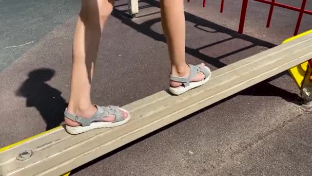 Een Meisje Sandalen Wandelingen Balanceren Een Houten Bar Speelplaats — Stockvideo