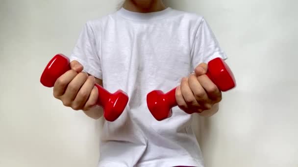 Dívka Bílém Tričku Pomalu Pohybuje Dvěma Červenými Činkami Hmotnosti — Stock video