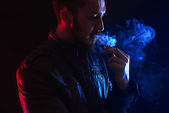 dobře oblečený vousatý muž kouření elektronické cigarety ve studiu