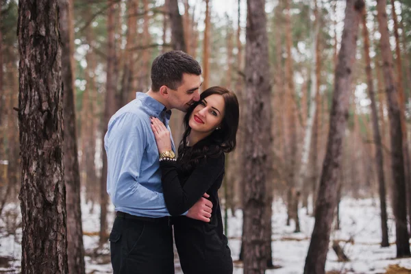 Fiatal csinos pár átölelve téli erdőben. Téli szerelmi történet — Stock Fotó