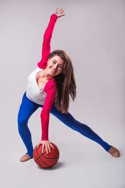 青年女子篮球球员与球的画像。美丽的白种女人运动服在灰色的背景上打篮球 — 图库照片