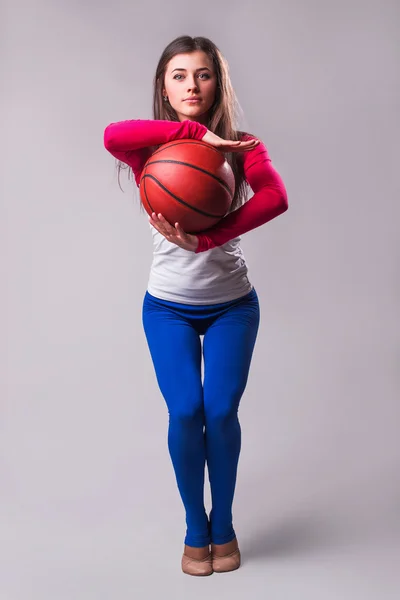 Retrato de una joven jugadora de baloncesto con pelota. Hermosa mujer caucásica en ropa deportiva jugando baloncesto sobre fondo gris — Foto de Stock