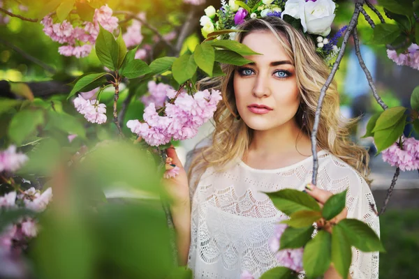 Spring beauty meisje met lange rode haren buiten waait. Bloeiende sakura boom. Romantische jonge vrouw portret — Stockfoto