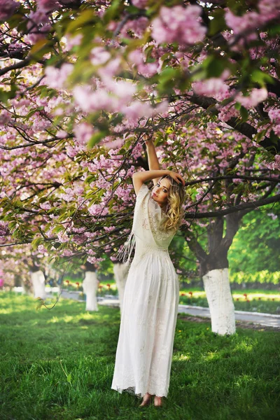 Uzun kırmızı üfleme saç açık havada bahar güzellik kız. Çiçek açan sakura ağacı. Romantik genç kadın portre — Stok fotoğraf